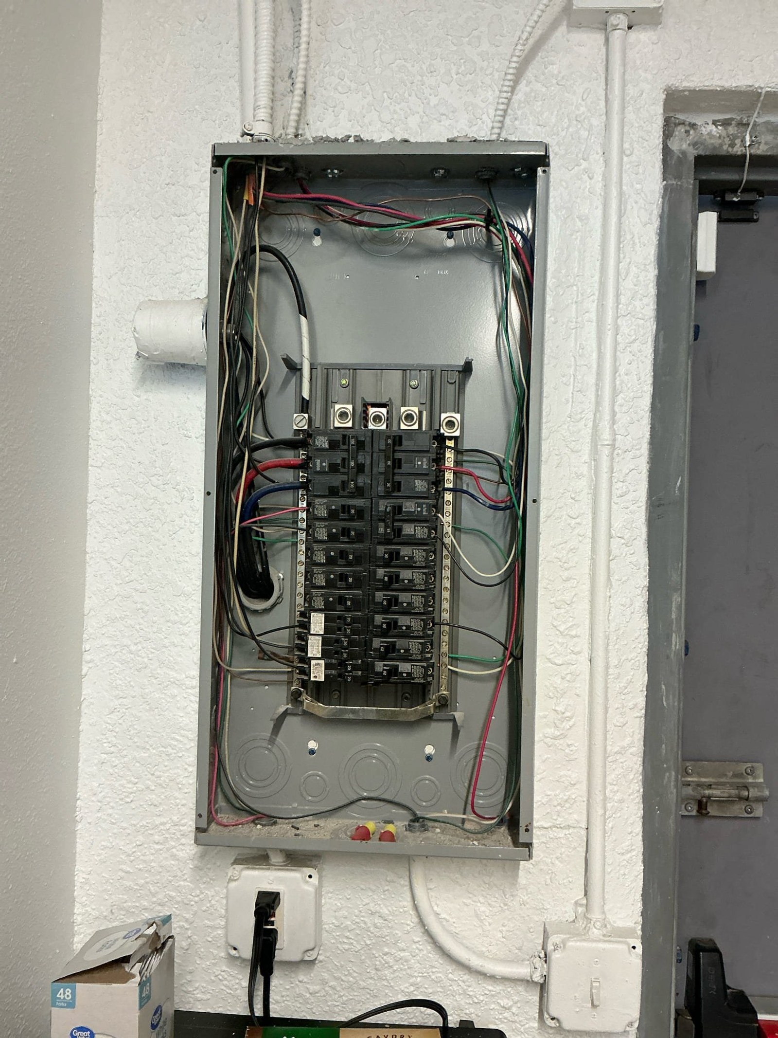 Secondary electrical subpanel showing missing 2-inch main bushing, inadequate wire protection at enclosure entries, and loose ground connections.