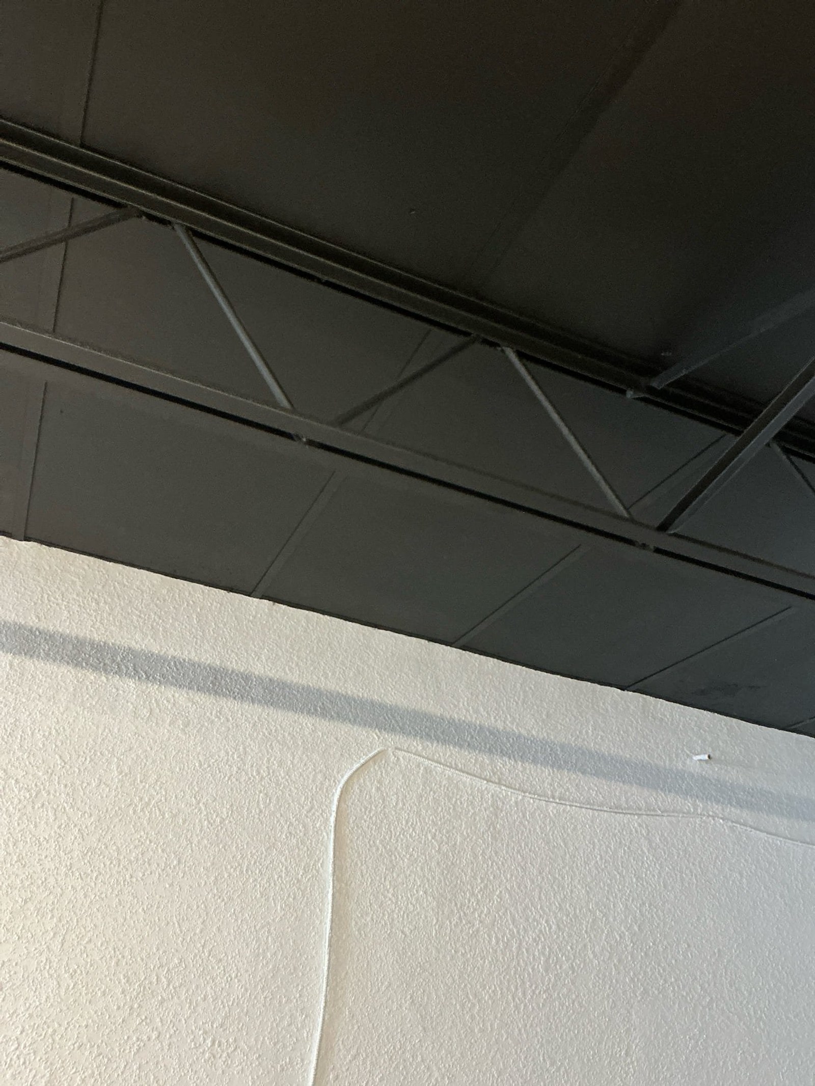 Ceiling area with exposed wiring raceway showing unprotected wire entry into ceiling structure.