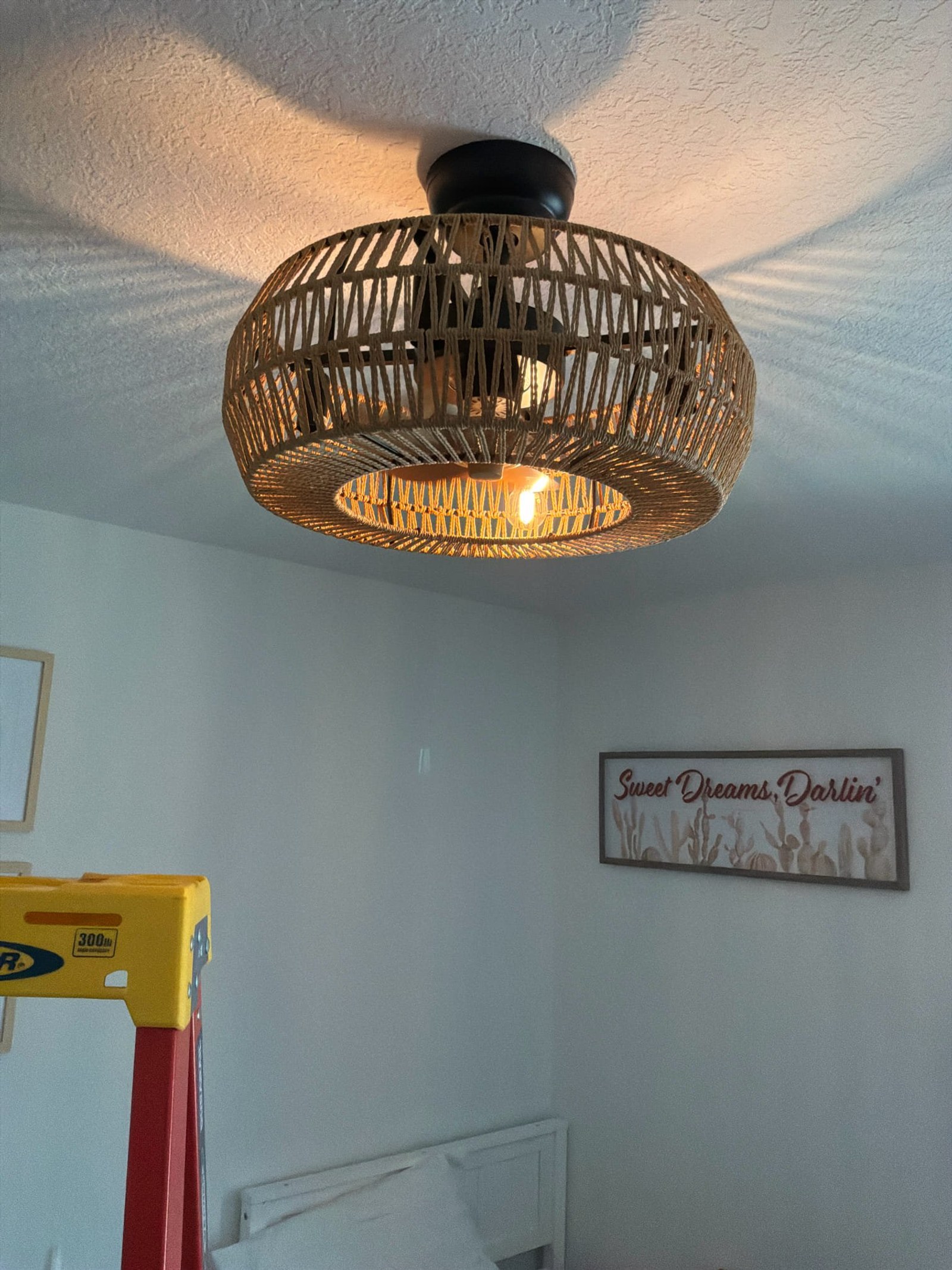 Newly installed ceiling fan fixture with woven shade showing proper mounting and clean installation finish.