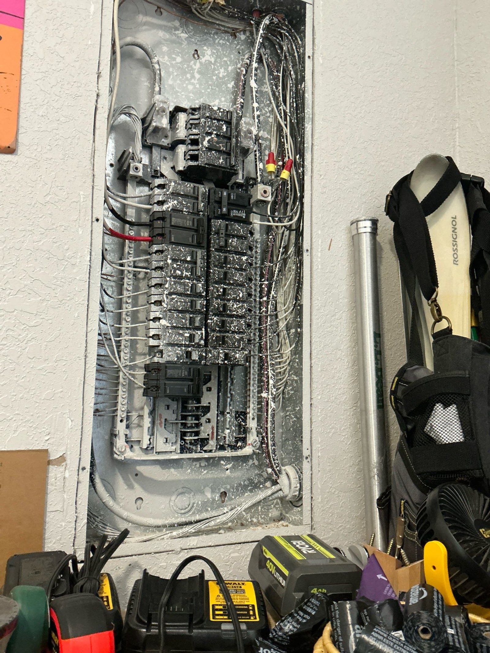 Full electrical panel exterior showing corrosion damage, missing components, and improper wiring with technician tools visible at bottom.