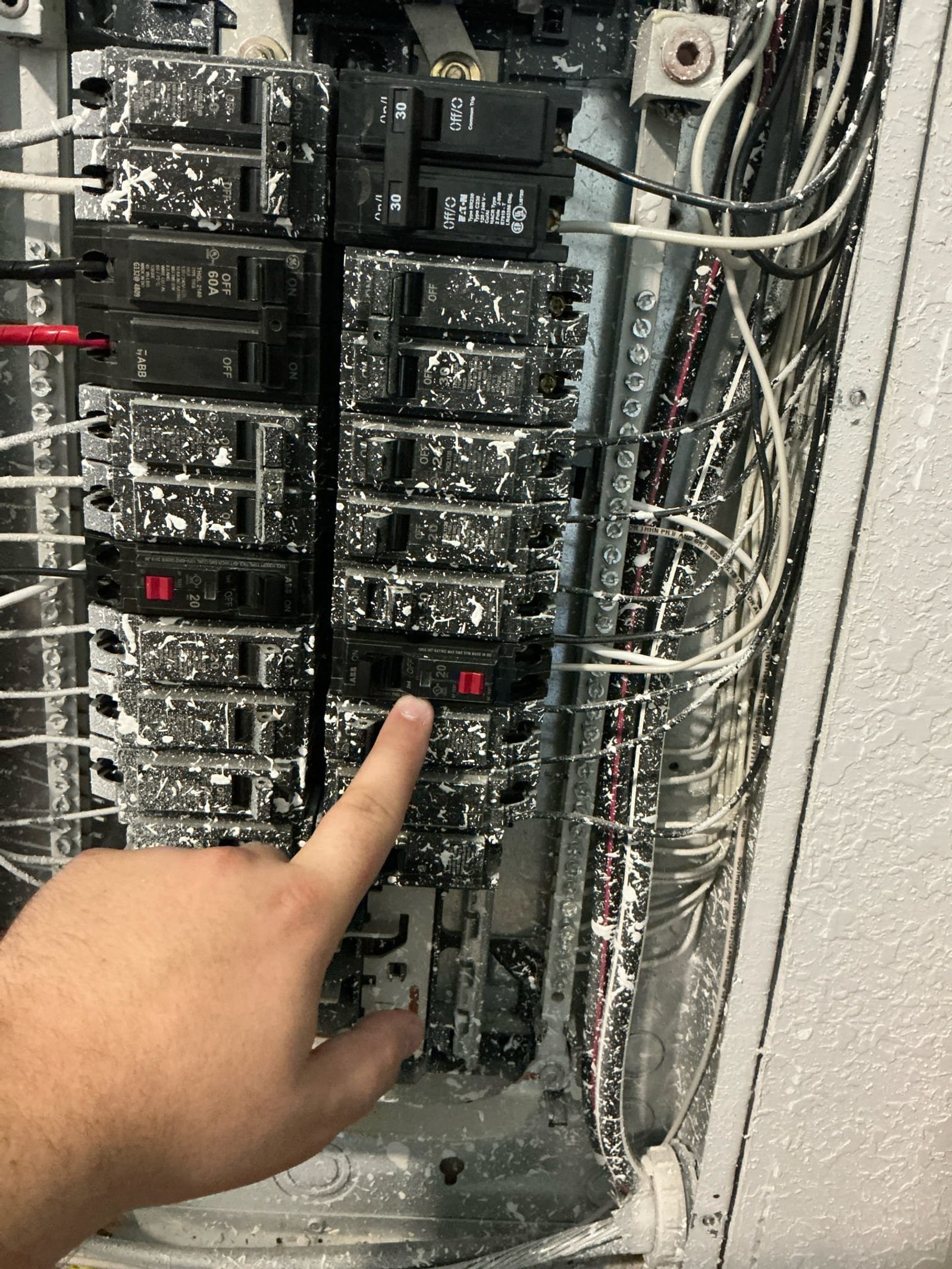 Panel interior with technician's finger pointing to missing arc fault breaker and demonstrating corroded terminal connections requiring replacement.