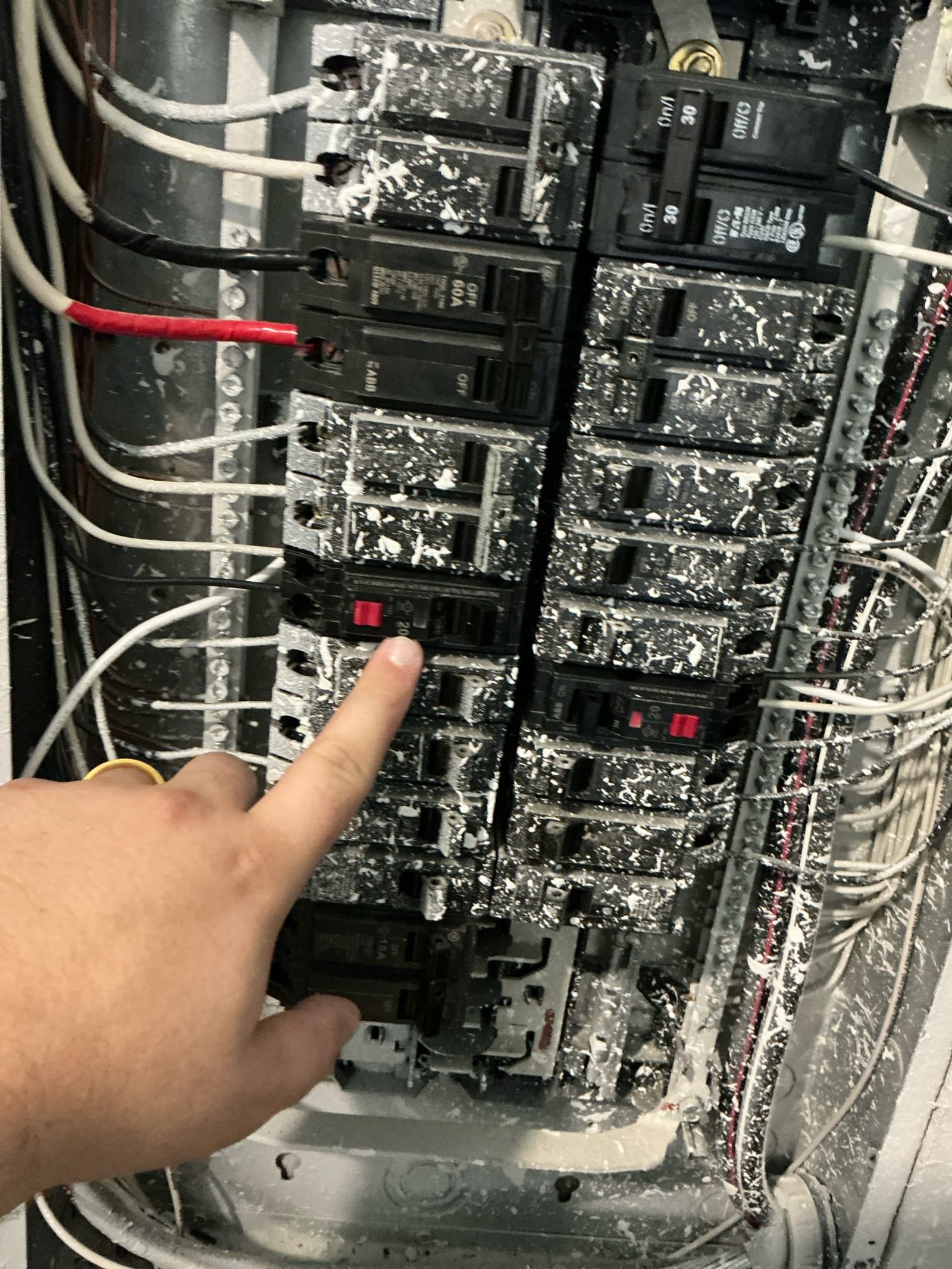 Panel interior close-up with technician pointing to improperly terminated conductor and corrosion demonstrating lack of arc fault protection.