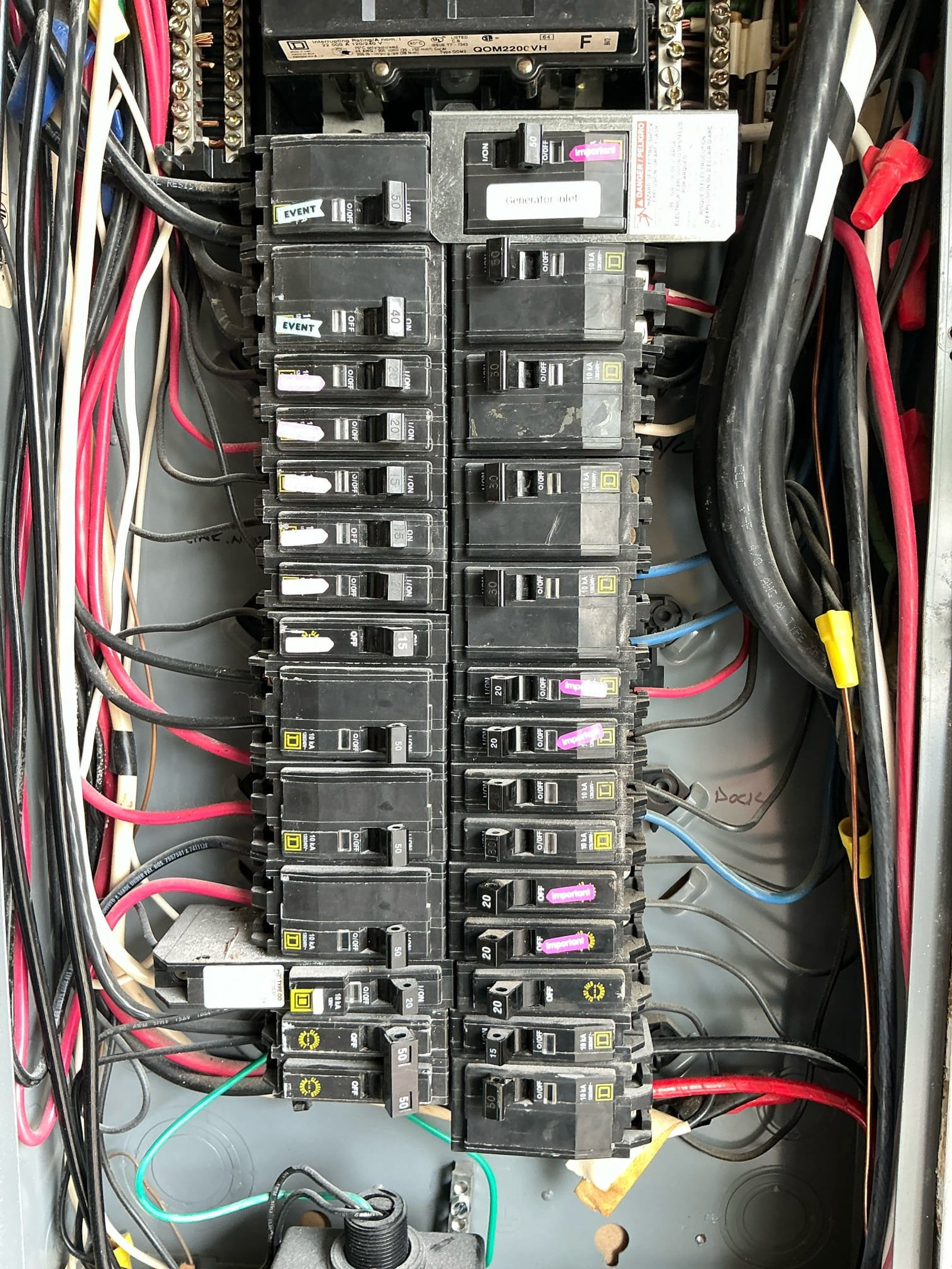 Main panel breaker array showing two columns of mixed 20-amp and 40-amp breakers with EVENT brand protection devices installed side-by-side in violation of panel design specifications.