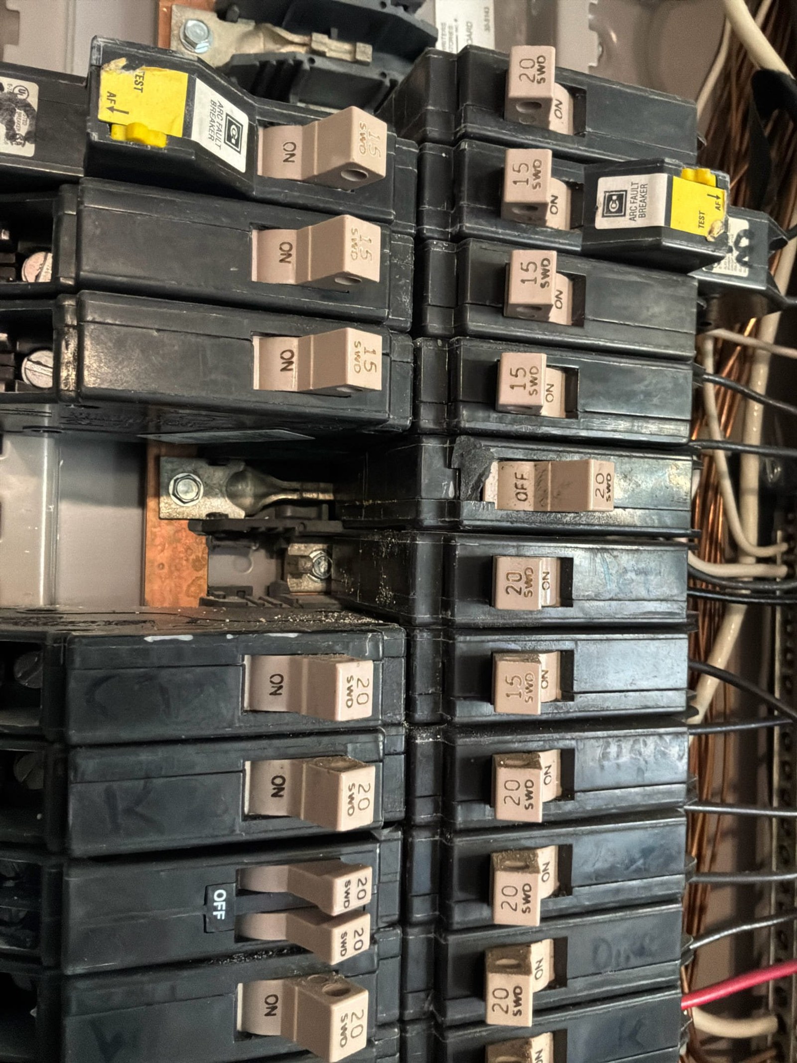 Breaker panel detail showing mixed breaker sizes and missing arc-fault and GFCI breakers with manual labels on tan breakers.