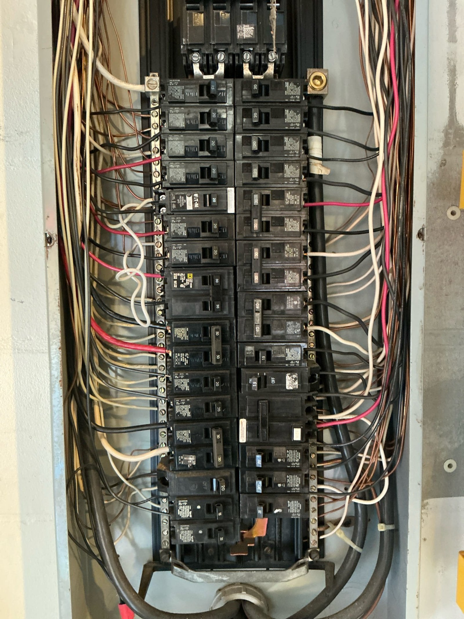 Panel interior showing full breaker configuration with multiple tangled conductors and red connections indicating potential hazards.