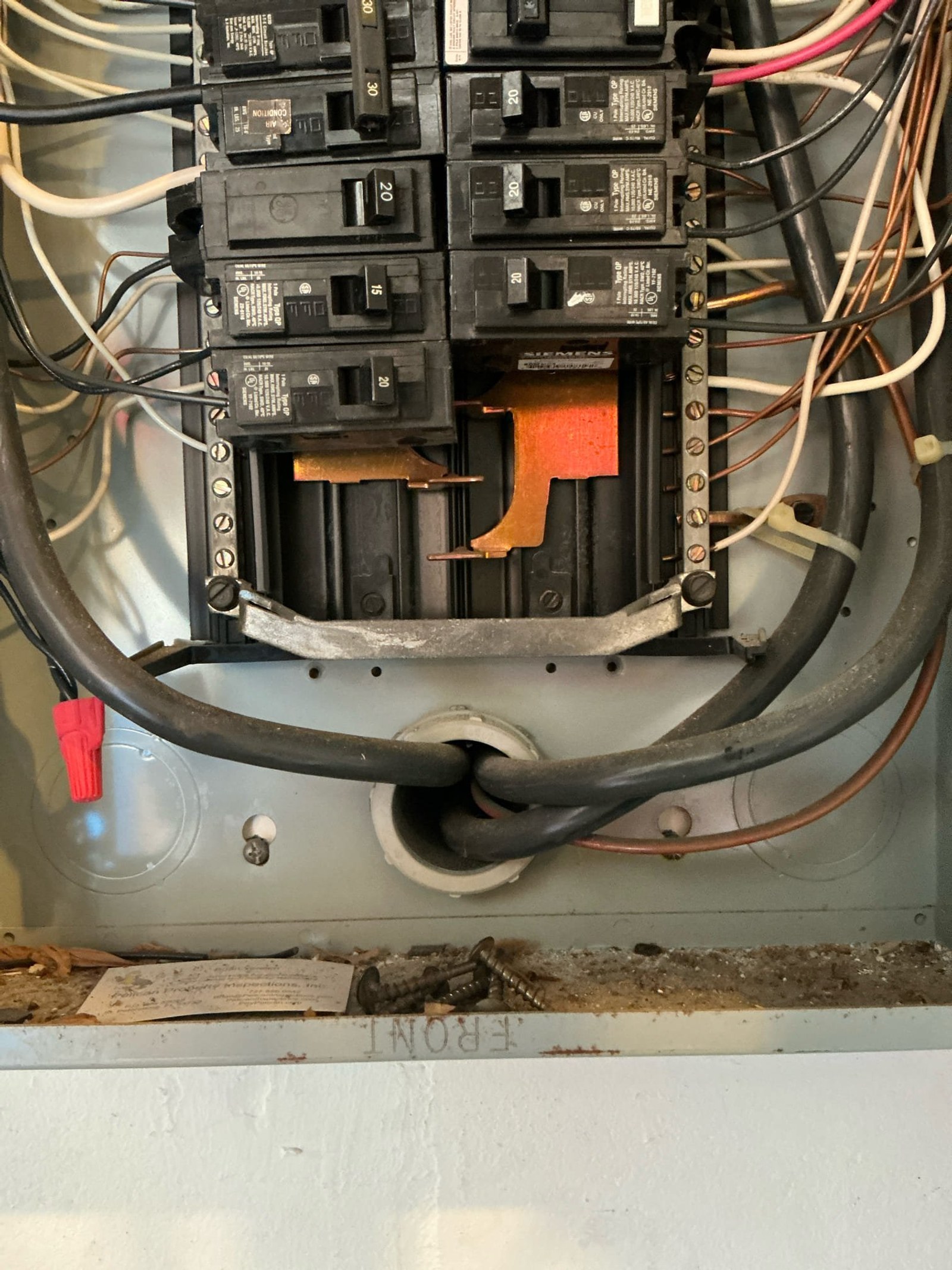 Close-up of panel main lug area showing corroded copper connection lugs and orange corrosion debris on neutral and ground bus bars.