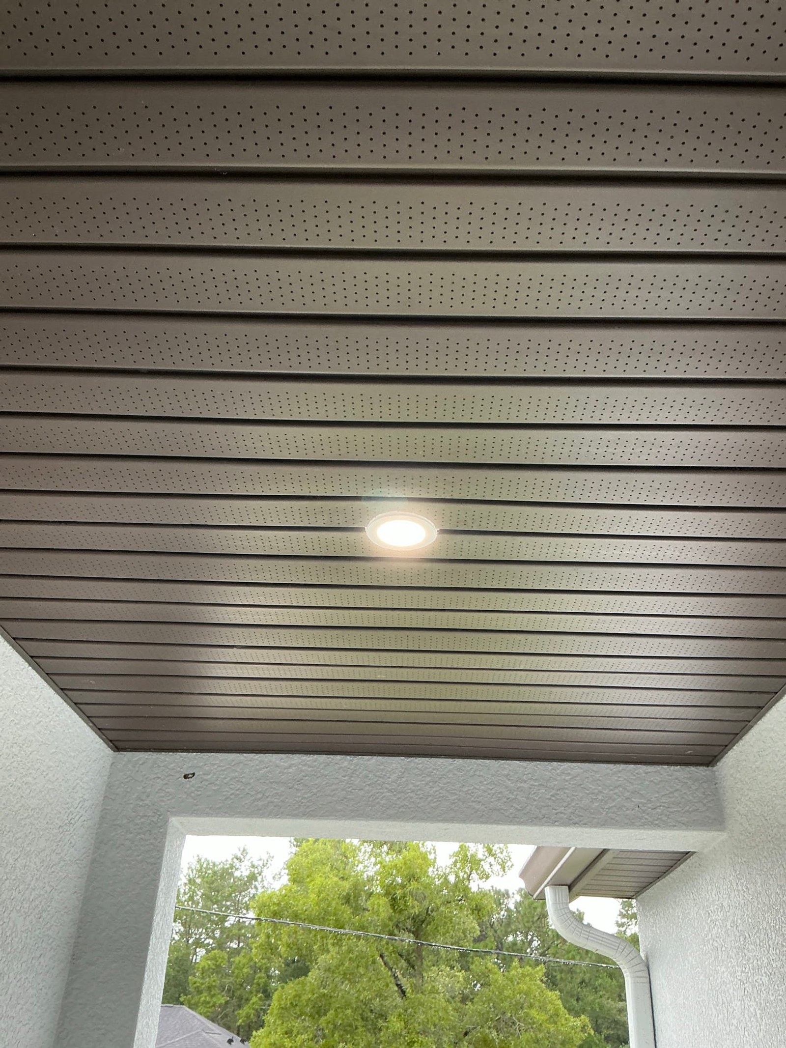 Porch ceiling with newly installed recessed LED light fixture operational and lit.