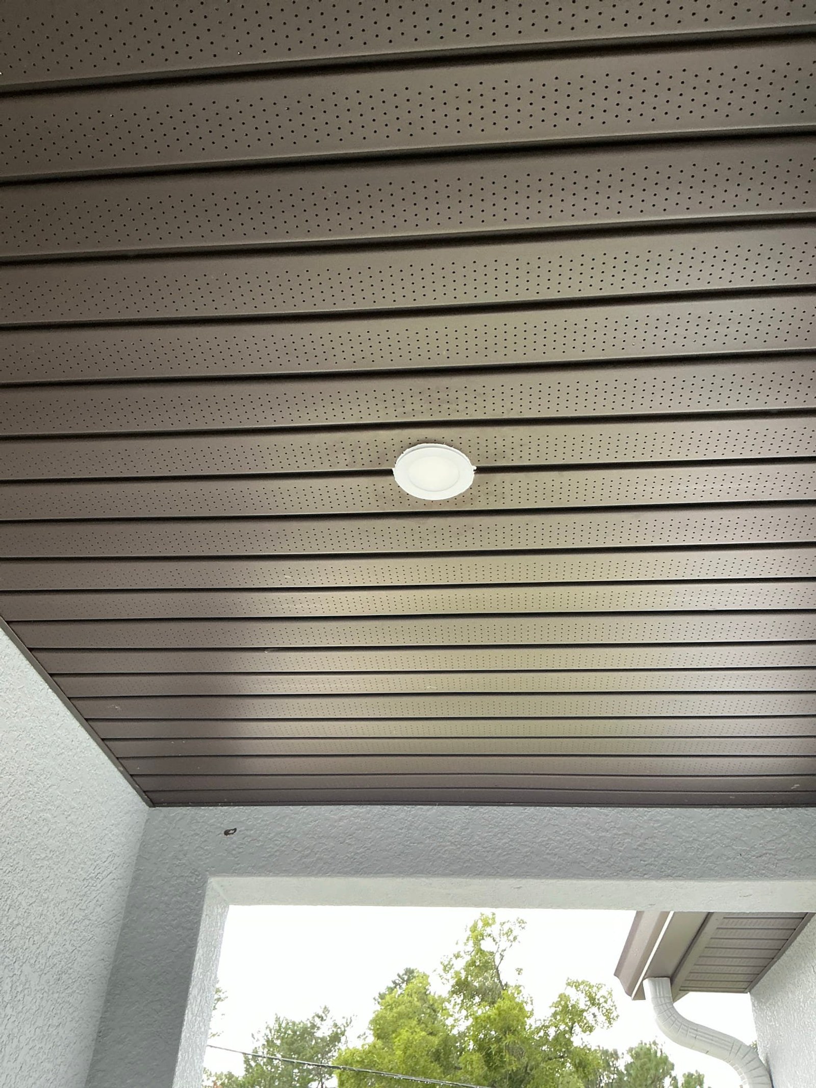 Porch ceiling showing new recessed light fixture in metal soffit.