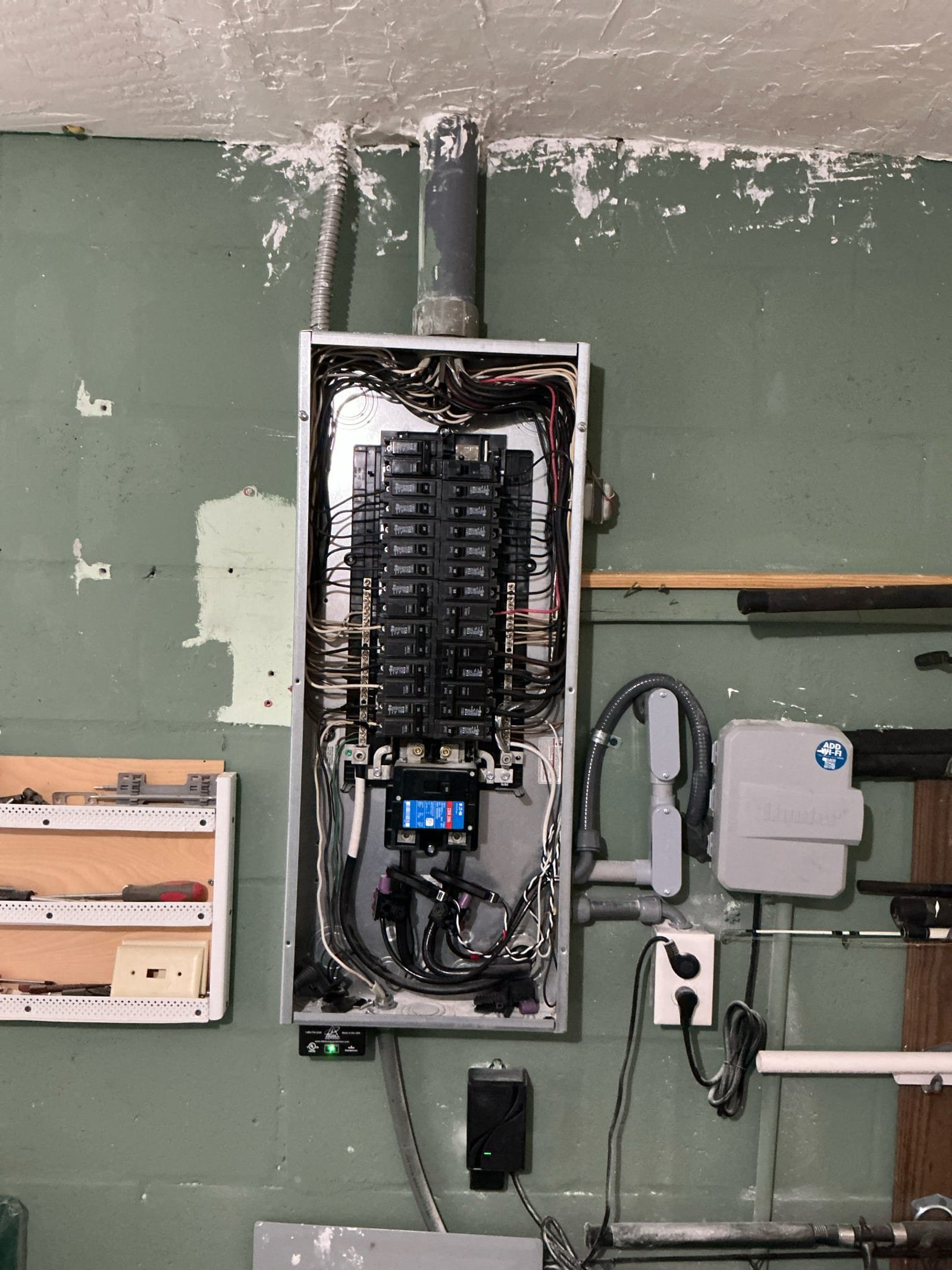 Sub-panel interior showing organized breaker layout with clear circuit labels, proper wire routing, and blue disconnect device, representing corrected/new installation work.