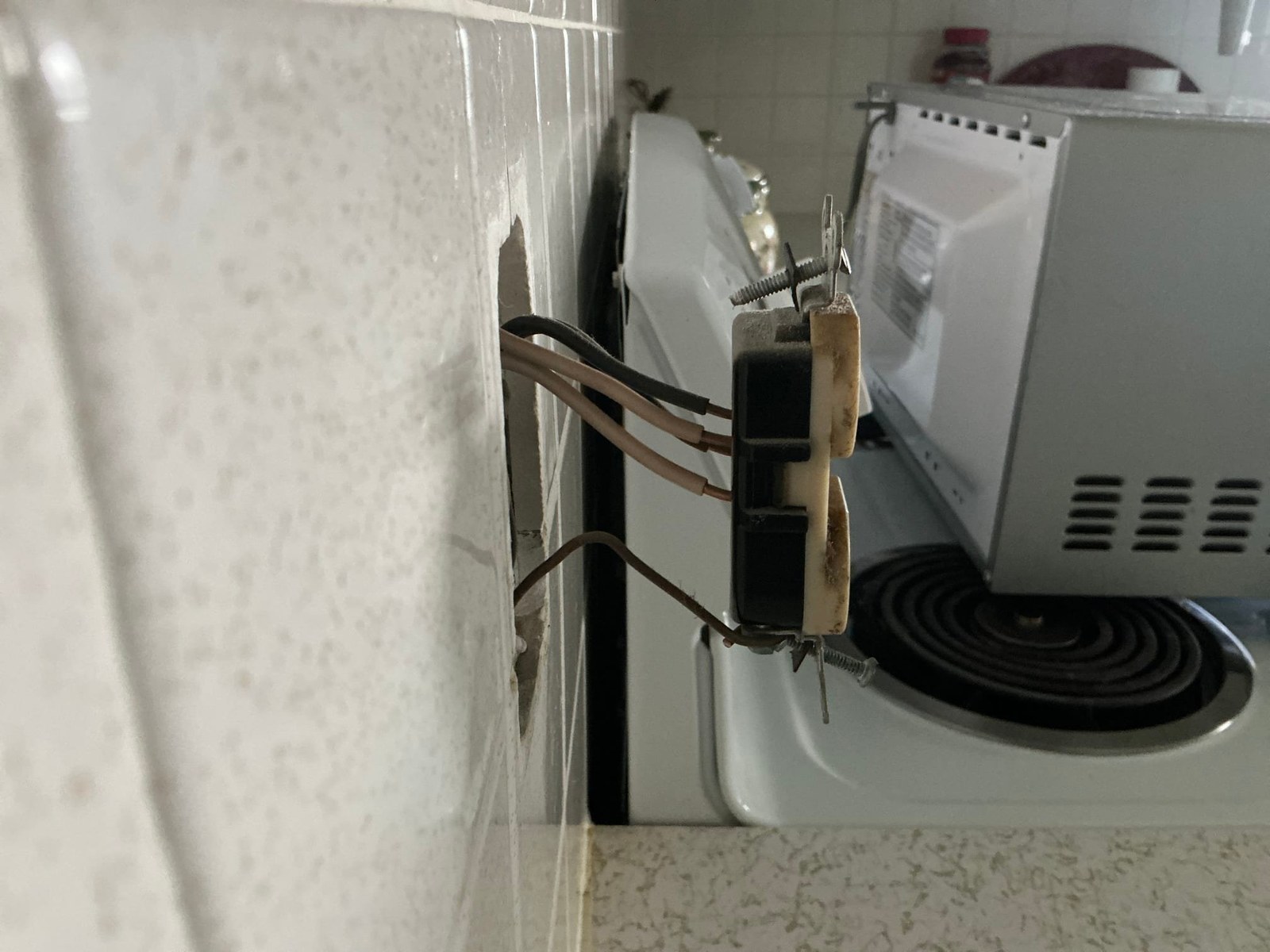Backstabbed two-wire outlet connection with unidentified black and brown wires pushed into spring terminals without strain relief or proper termination method.