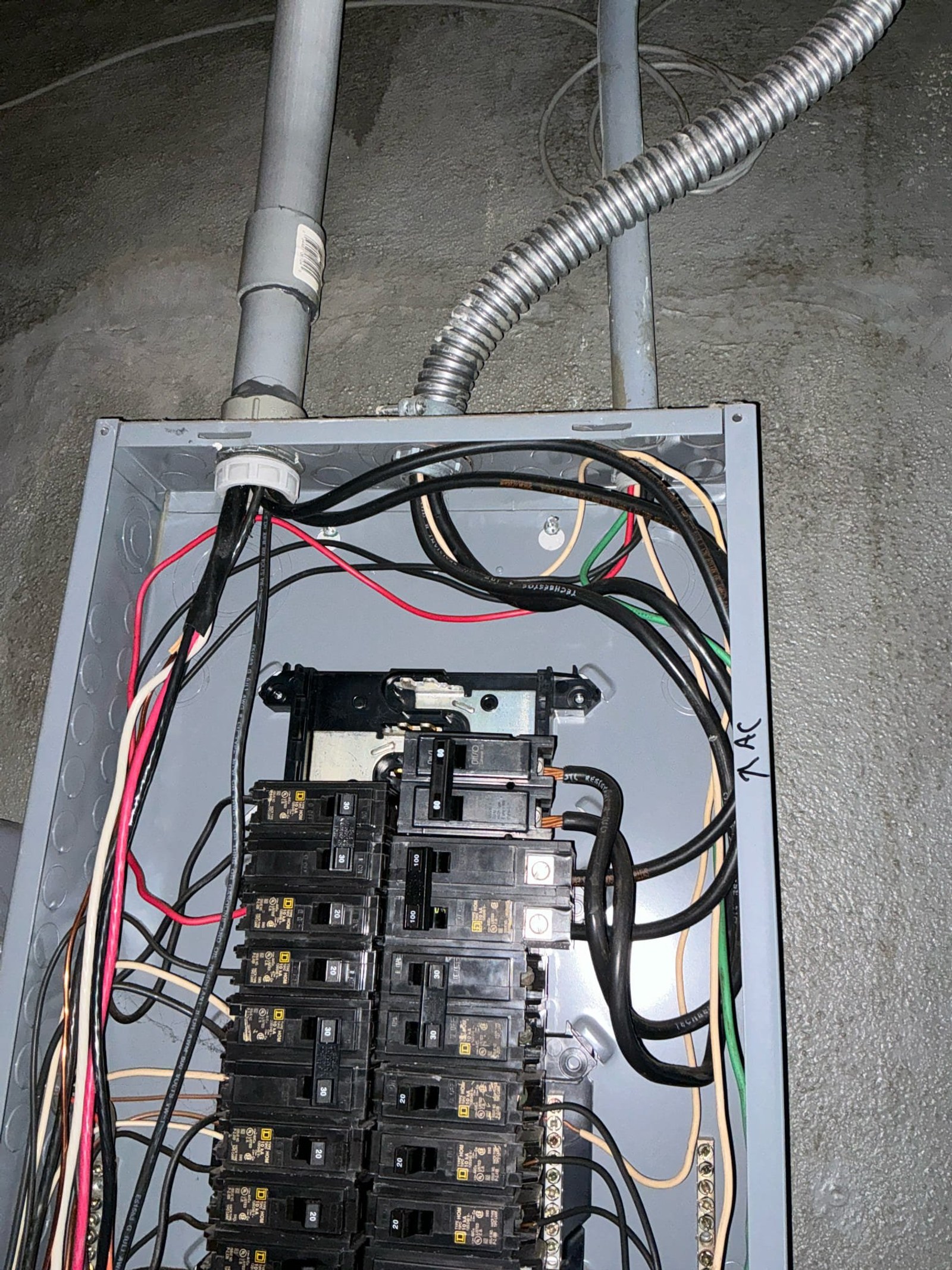 Sub-panel interior showing properly terminated breaker connections with organized wiring and protective conduit entries after corrections.